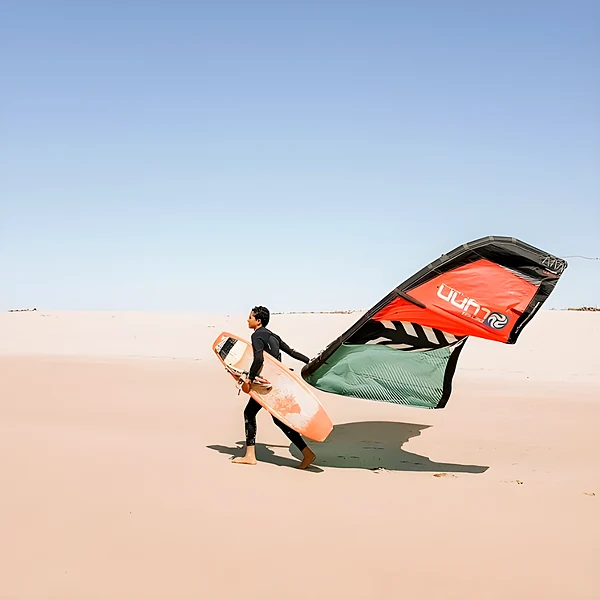 Kitesurfeur avec sa voile sur une plage de sable