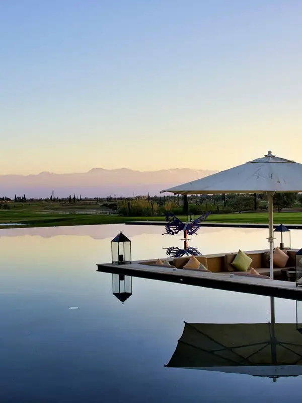 Lake and outdoor lounge beside a golf course, the Atlas in the background, Marrakech