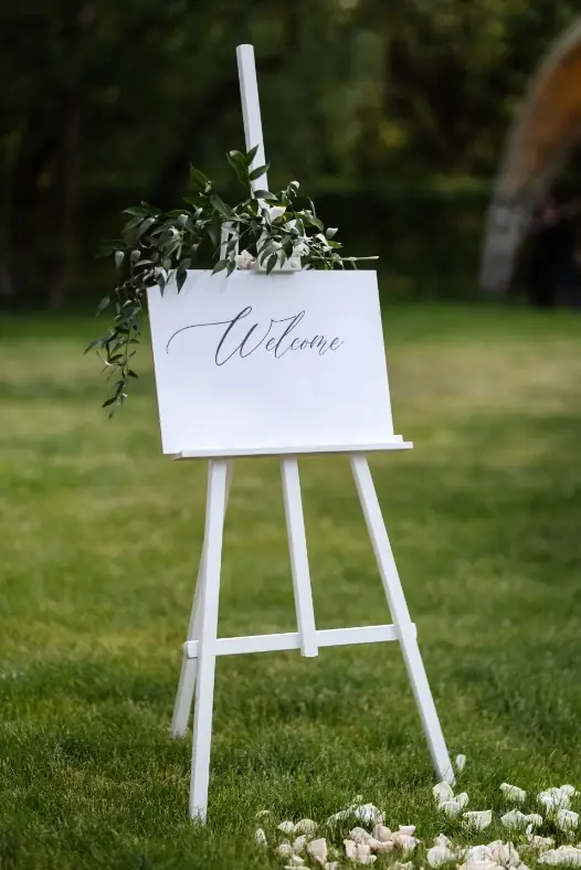 Flower-decked welcome easel on a lawn, event reception