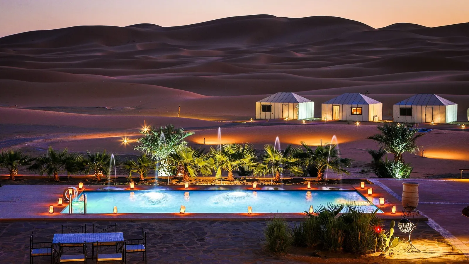 Campo di lusso e la sua piscina illuminati ai piedi delle dune