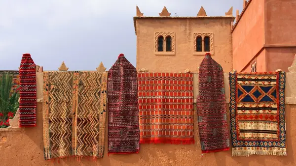 Berber rugs hanging in front of a rammed-earth kasbah