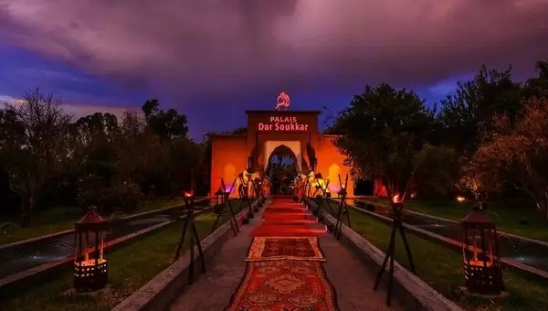 Path of lanterns and red carpet leading to an illuminated palace, Marrakech