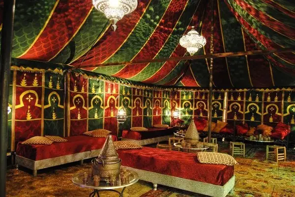 Interior of a caidal tent with red rugs and lanterns
